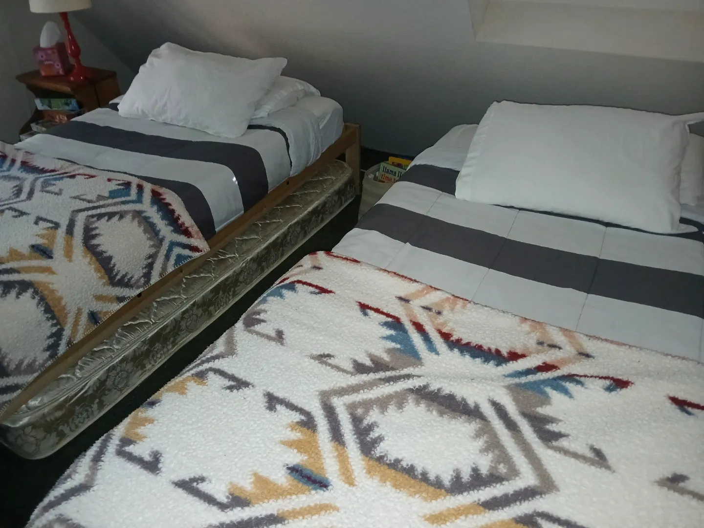 Twin beds in the loft with cozy blankets and a basket of kids' books
